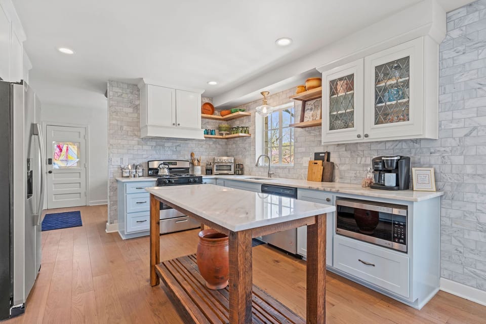 Bright, fully equipped kitchen with marble countertops, gas range, stainless steel appliances, and a spacious prep island—perfect for cooking meals at home during your Kansas City stay.