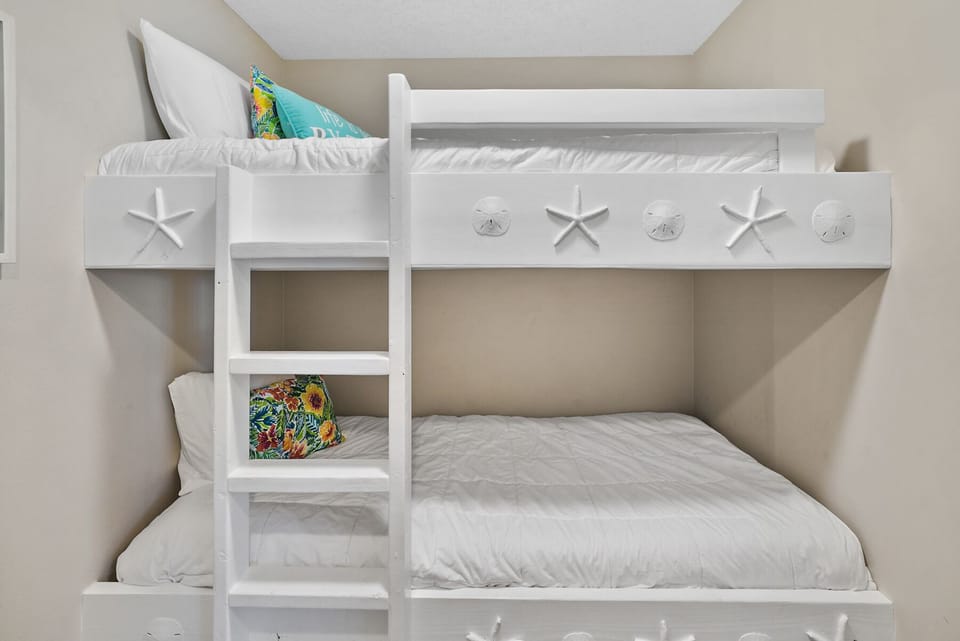 Your kids will love this coastal-themed bunk bed with charming starfish details and colorful tropical pillows for dreamy beach adventures.