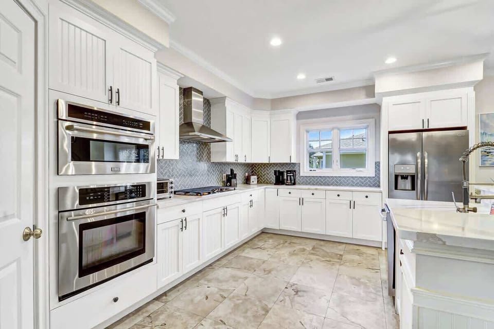 Your gourmet kitchen features crisp white cabinetry, sleek stainless steel appliances, and elegant marble countertops for memorable meal preparation.