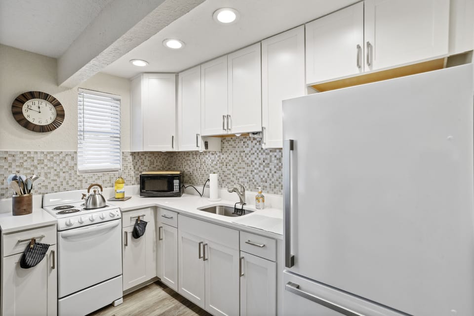 Contemporary kitchen with microwave, keurig coffee machine, fridge and freezer and plenty of utensils/dish ware for cooking.