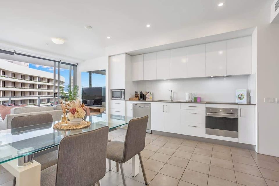 Gather around the dining table for relaxed meals after a day exploring the reef and waterfront, with natural light flowing through the open-plan space.