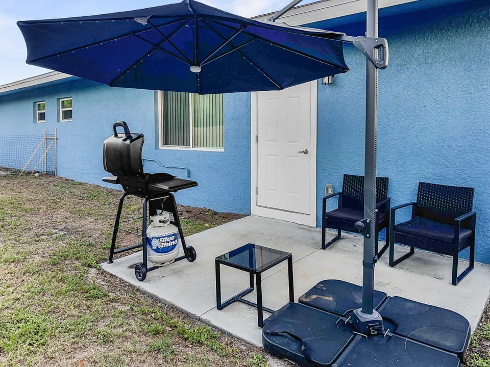 Outdoor patio with umbrella, patio seating, and gas grill against the home exterior