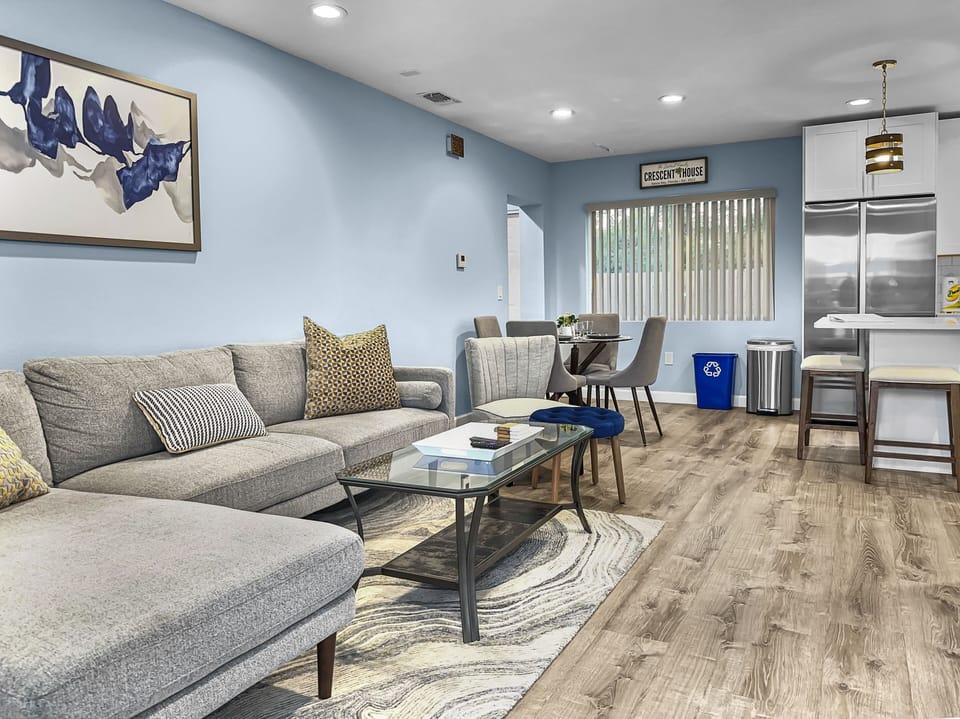 Open-plan living room and kitchen area from alternate angle showing sofa and stainless appliances