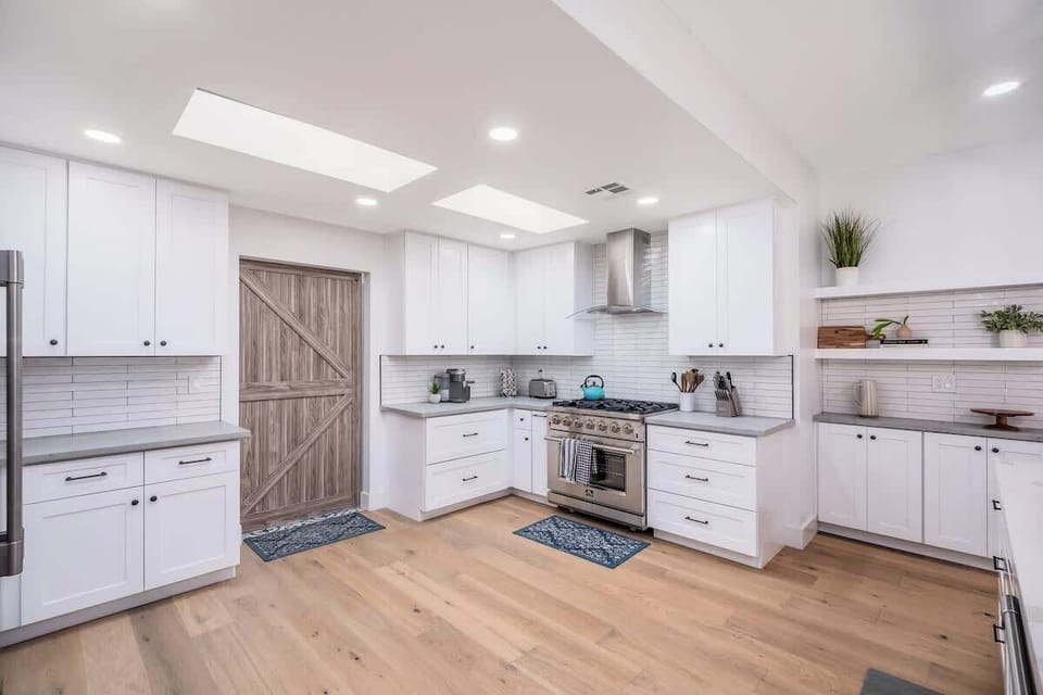 Step into your bright, airy kitchen where crisp white cabinetry and warm wood floors invite you to cook, gather, and make memories. Natural light pours through skylights as you prepare meals on professional-grade appliances.