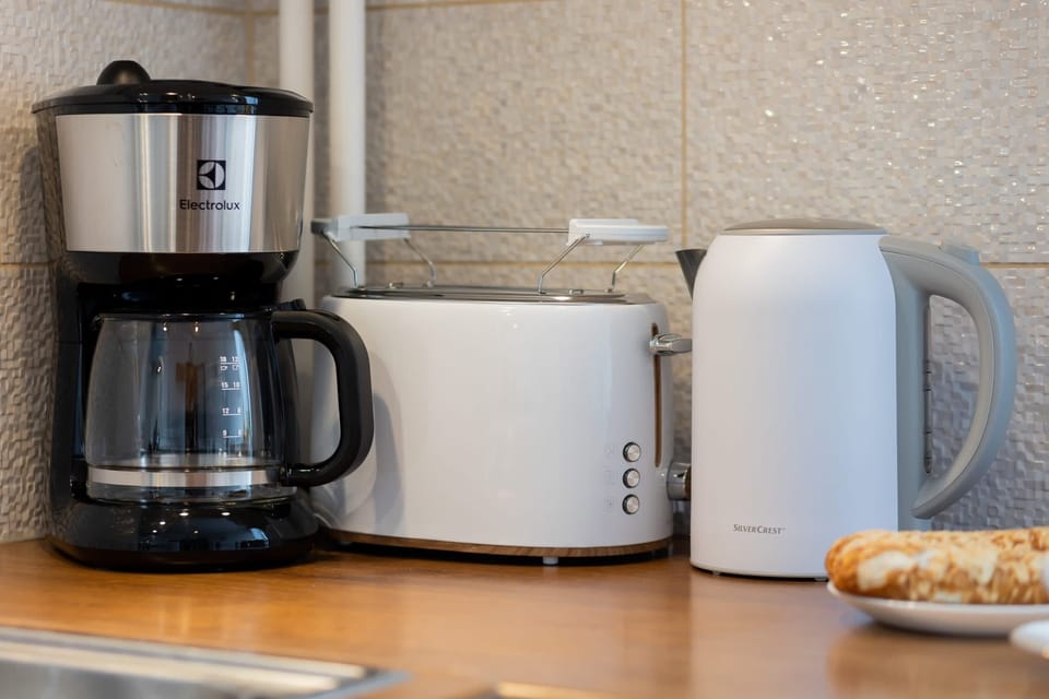A close-up of the coffee maker, kettle, and cups, emphasizing the apartment’s cozy and functional kitchen setup.