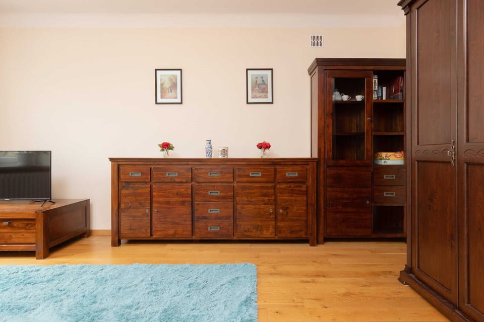 Another view of the living space, highlighting the sofa, a wooden dresser, and light wooden floors.