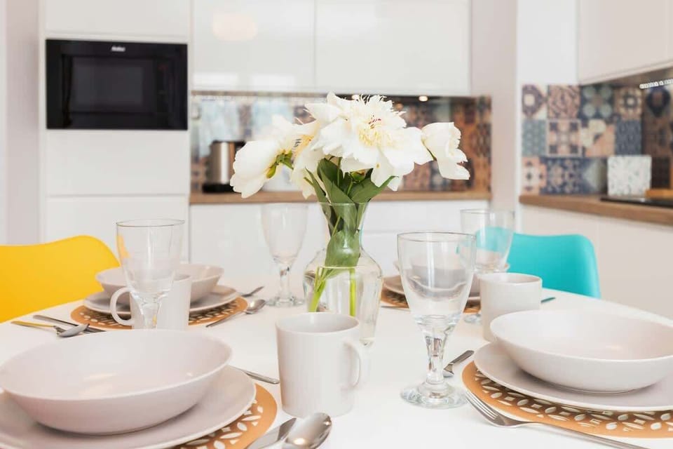 A close-up of a dining table set for a meal, with white plates, glasses, and fresh flowers in the center.