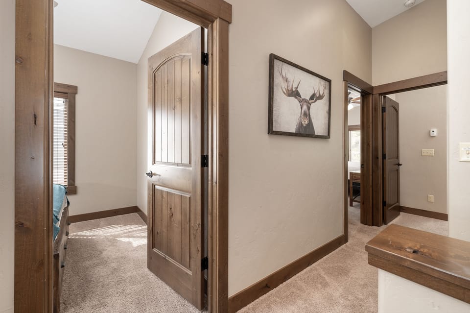 - Light filled hallway with vaulted ceiling and rustic doors welcomes guests - Moose print on the wall adds mountain personality to this charming space - Leads to multiple bedrooms and living areas for easy home flow