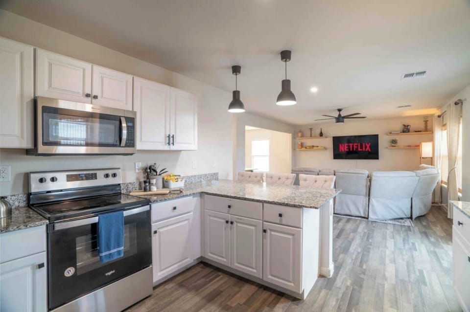 Fully equipped kitchen with stove, microwave, and white cabinetry.