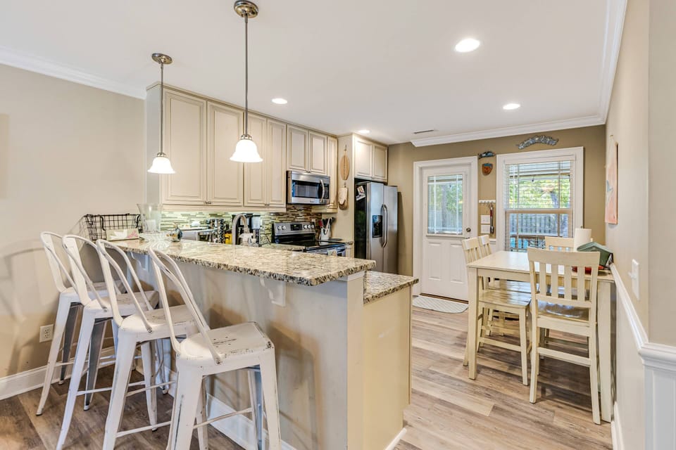 Open kitchen-dining area: granite island, pale cabinets, plenty of light, perfect for meals.