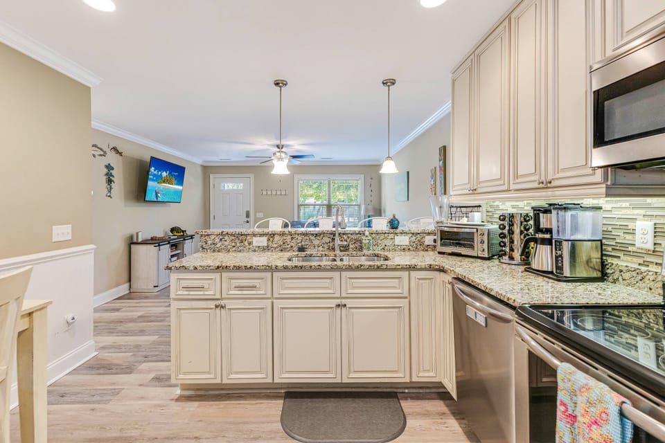Open kitchen with modern appliances on the counter: microwave, toaster oven, drop coffee maker, blender, and more.