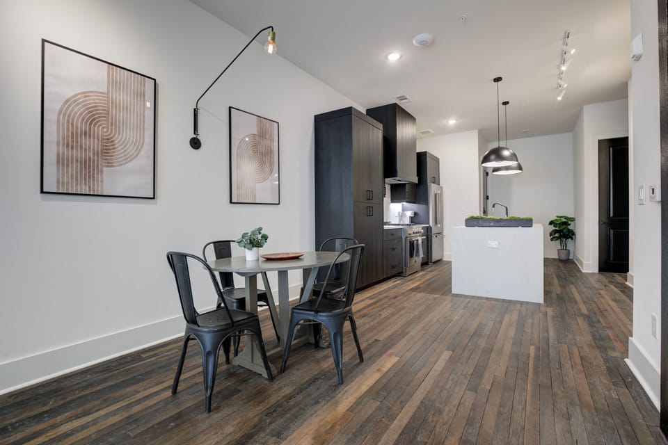 Dining nook flows into kitchen w/ wood floors, modern lighting & open layout