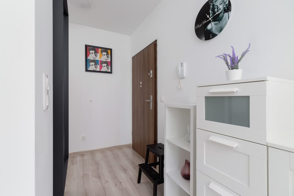 The entrance area of the apartment, featuring a white cabinet, a white wardrobe and a wall clock. The space is well-organized and functional.