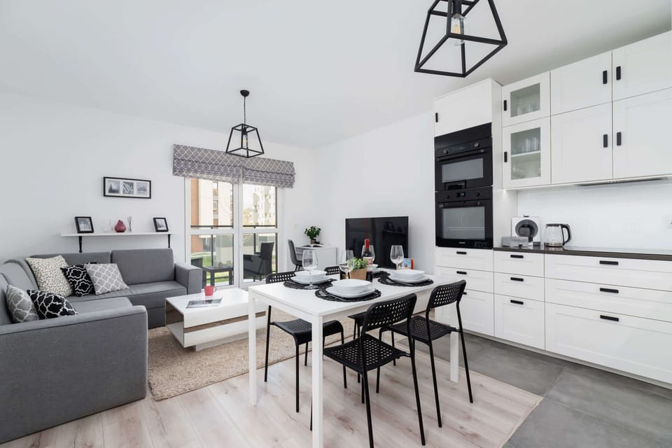 The kitchen and dining area viewed from another angle, emphasizing the bright and airy atmosphere. The black-and-white contrast adds a modern touch.