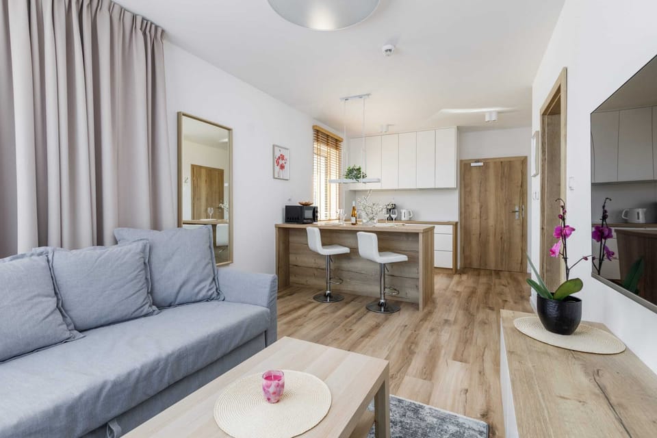 A living room with a gray sofa, a wooden entertainment center, and access to a balcony.