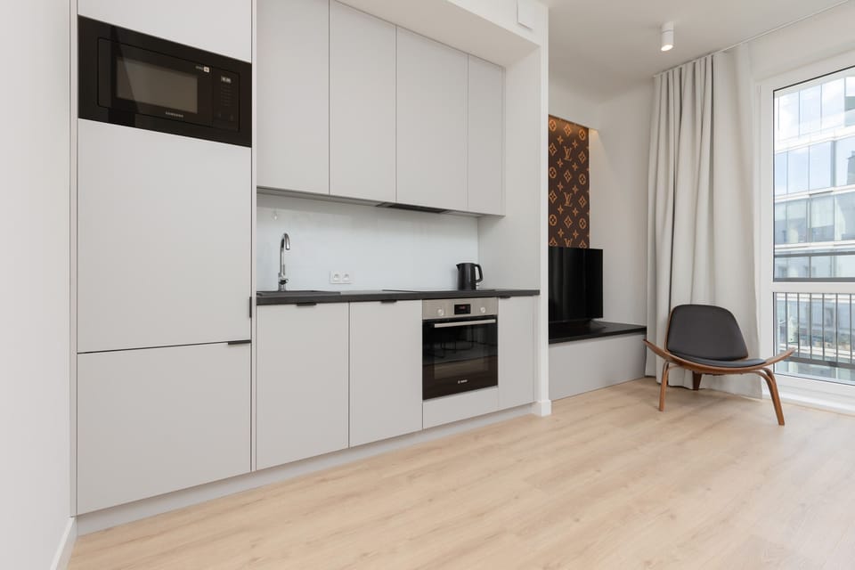 A compact yet modern kitchen with sleek white cabinetry and integrated appliances.
