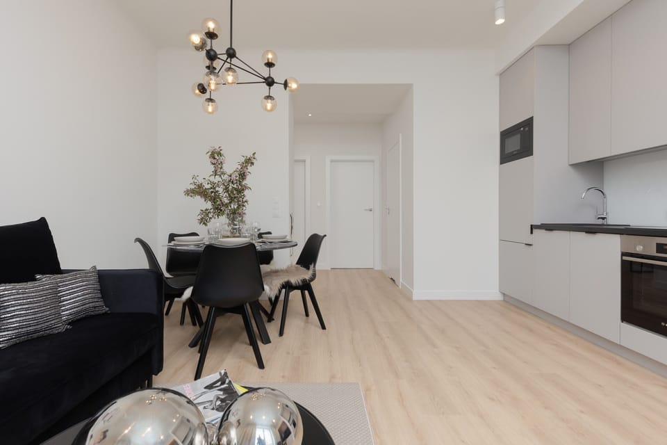 A chic dining setup featuring a round table, comfortable black chairs, and a decorative chandelier above.