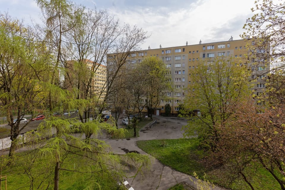 A view of the nearby area, featuring trees, greenery, and residential buildings, creating a serene environment.

