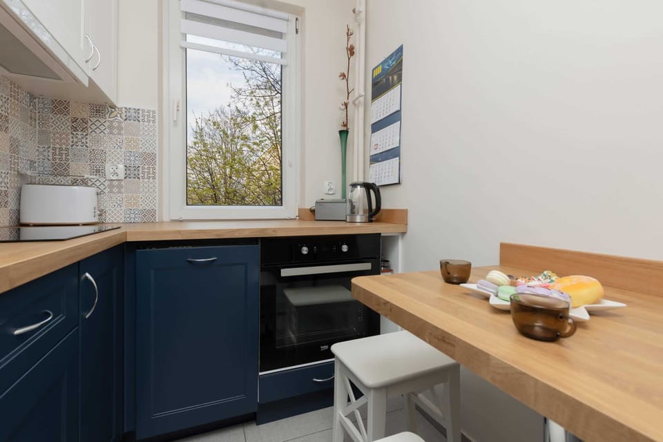 A compact kitchen with dark blue cabinets, wooden countertops, and modern appliances, ensuring convenience for cooking.

