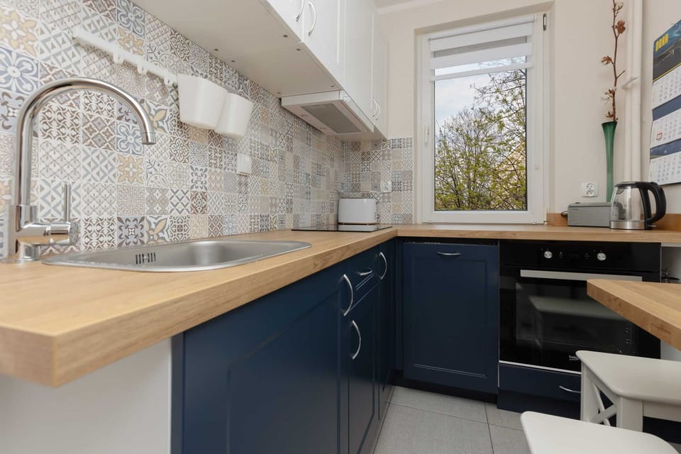 A bright kitchen with a large window, patterned backsplash, and well-organized cabinets for a modern, functional space.

