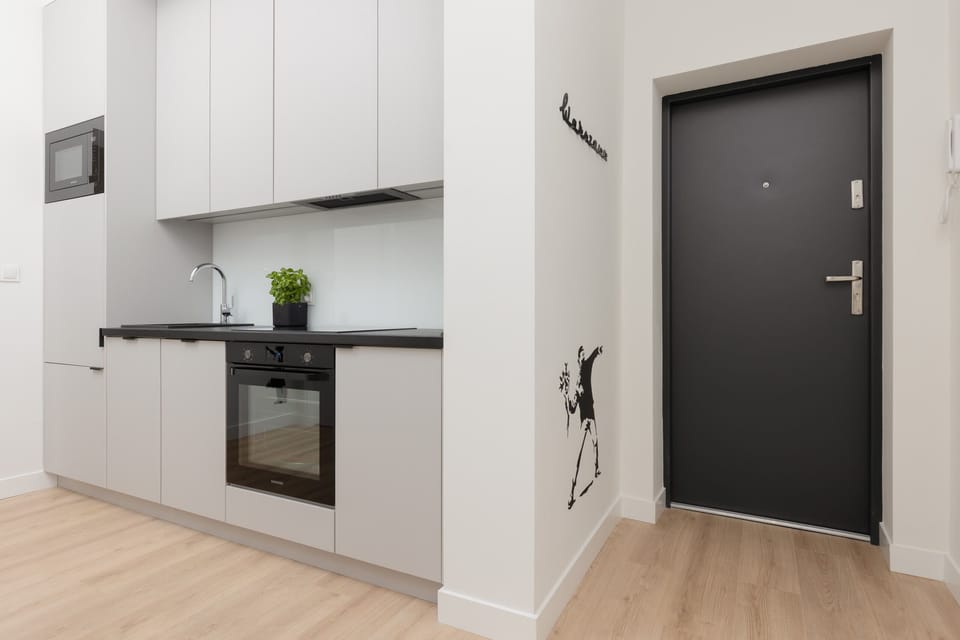 A sleek and compact kitchen with white cabinetry, black countertops, and modern appliances.