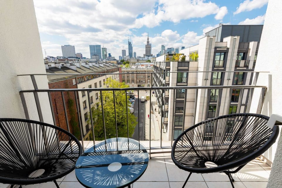 A cozy balcony with two black chairs and a small table, offering an excellent spot to enjoy the city views.