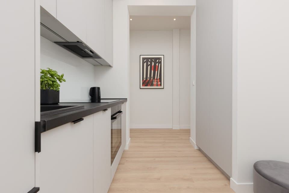 A sleek and compact kitchen with white cabinetry, black countertops, and modern appliances.