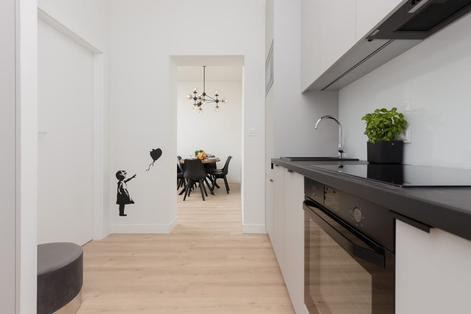 A sleek and compact kitchen with white cabinetry, black countertops, and modern appliances.