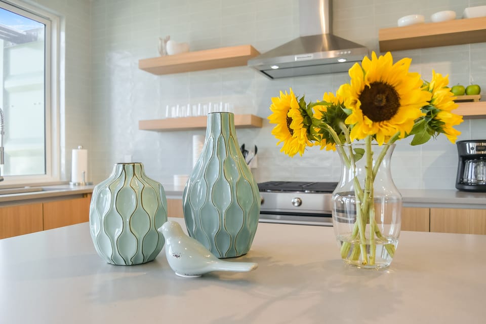 Bright sunflowers welcome you to your modern kitchen, where sleek appliances and warm wood shelving create the perfect space for preparing memorable meals.