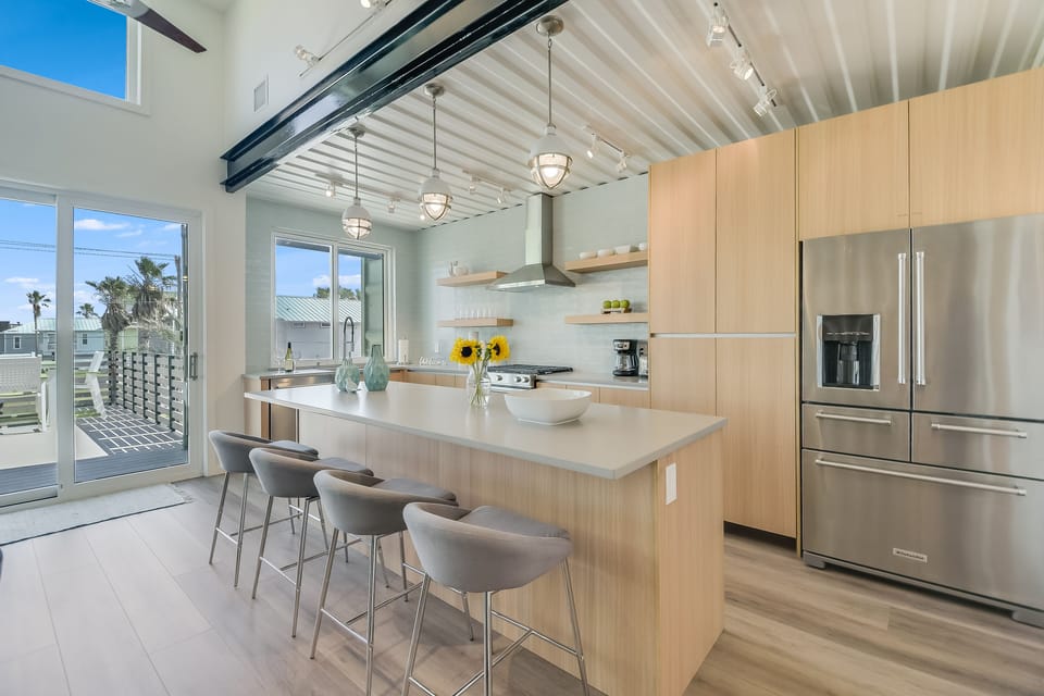 Cook and dine in this stunning modern kitchen featuring sleek appliances, spacious island seating, and beautiful natural light streaming through large windows.
