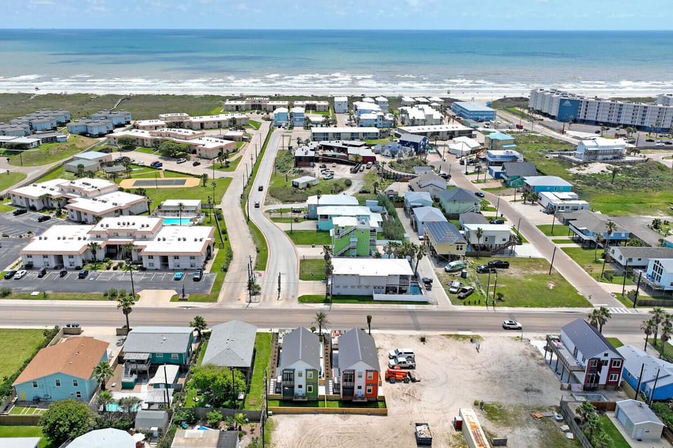 Aerial view of a vibrant coastal community with colorful beach houses and direct access to the shore.