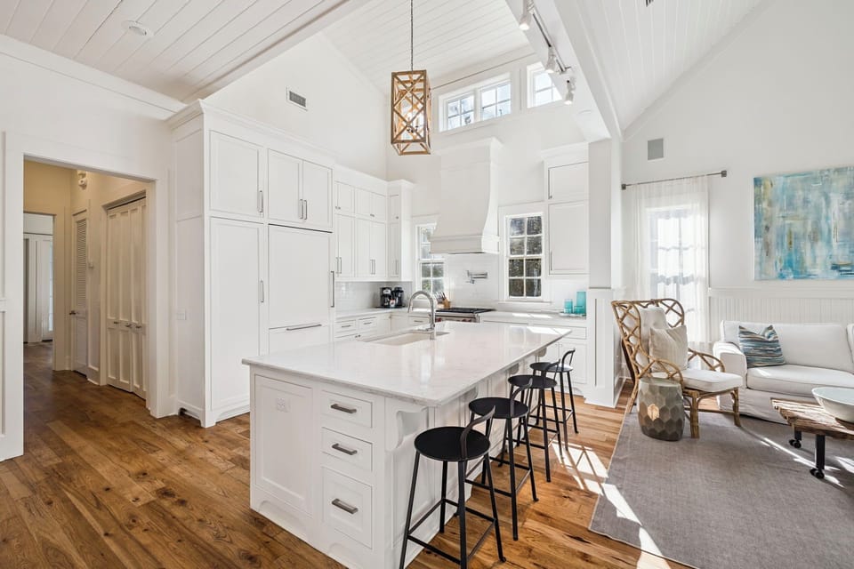 Your spacious kitchen island becomes the heart of gathering, with sleek white cabinets and warm wood floors creating the perfect cooking retreat.