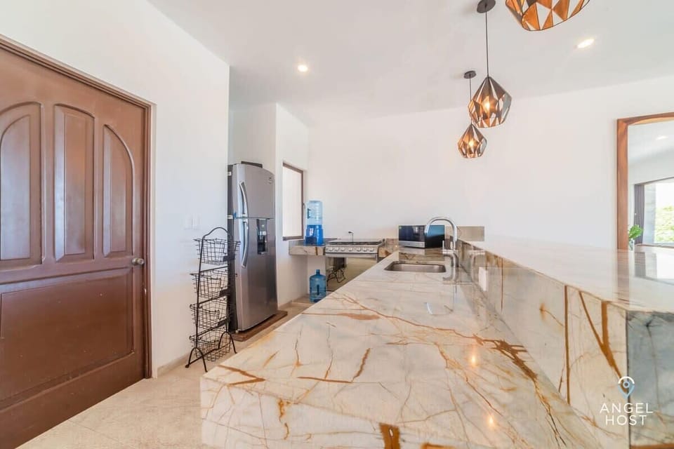 A spacious, modern kitchen with a beautiful countertop and all the appliances.