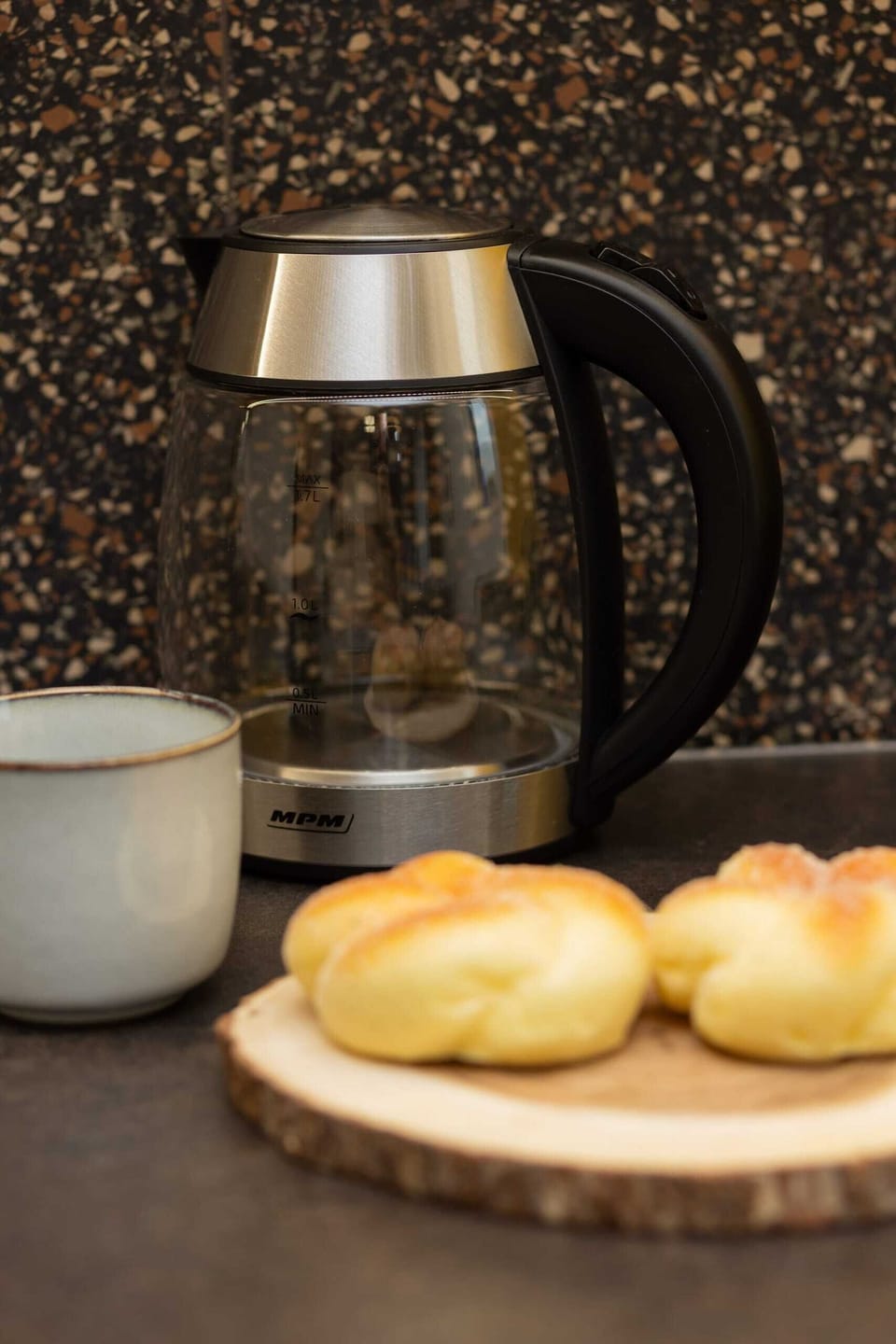 Close-up of a coffee maker and croissants on a wooden countertop, adding a cozy breakfast vibe.
