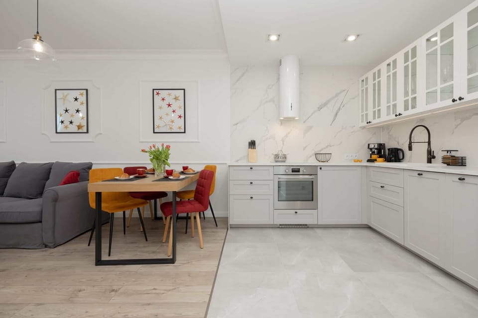 A view of the open kitchen and dining area, featuring white cabinets and a stylish modern layout.

