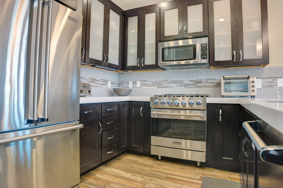 The kitchen with stainless steel Viking appliances, dark wood cabinets and neutral tiled backsplash.