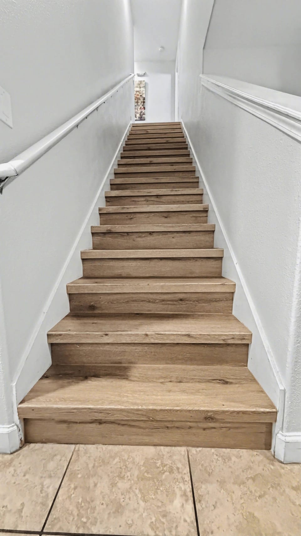 Interior staircase with wood-style flooring provides easy access between levels, with a handrail along the wall for added convenience.