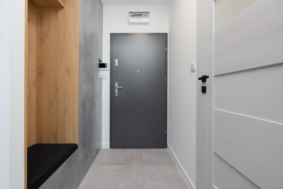 The apartment entrance featuring a sleek modern door with wooden accents.
