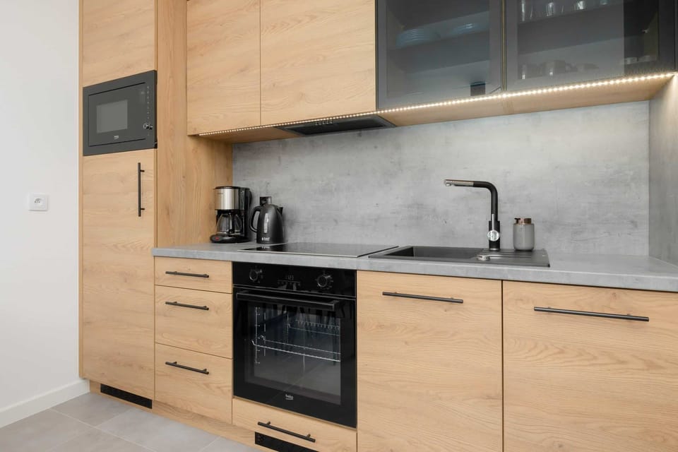 A sleek kitchen with wooden cabinetry, a built-in oven, and modern appliances, offering functionality and style.
