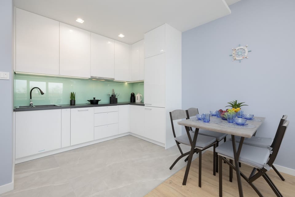 A compact dining and kitchen area with modern white cabinets and a small dining table.
