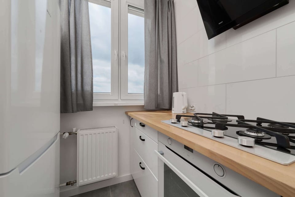 A well-equipped kitchen with a gas stove, white cabinetry, and a bright window for natural light.
