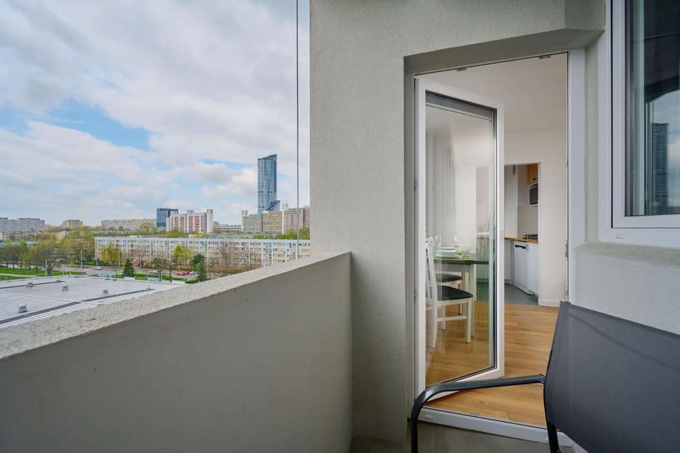 A balcony with a seating area, offering a serene view of the surrounding greenery and urban skyline.
