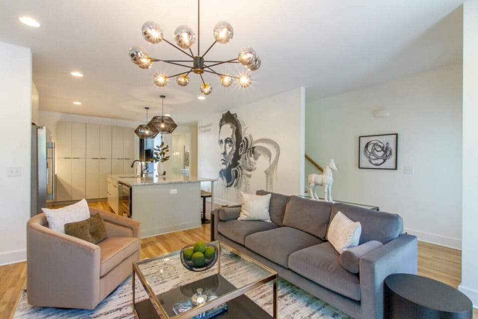 Bright living room with a sectional, chandelier, and striking portrait artwork