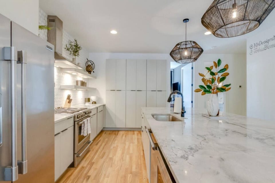 Sleek galley kitchen with white cabinetry, stainless range, and marble countertops