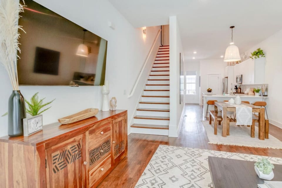 Living area with antique wood sideboard, plants, visible staircase, and open-plan layout