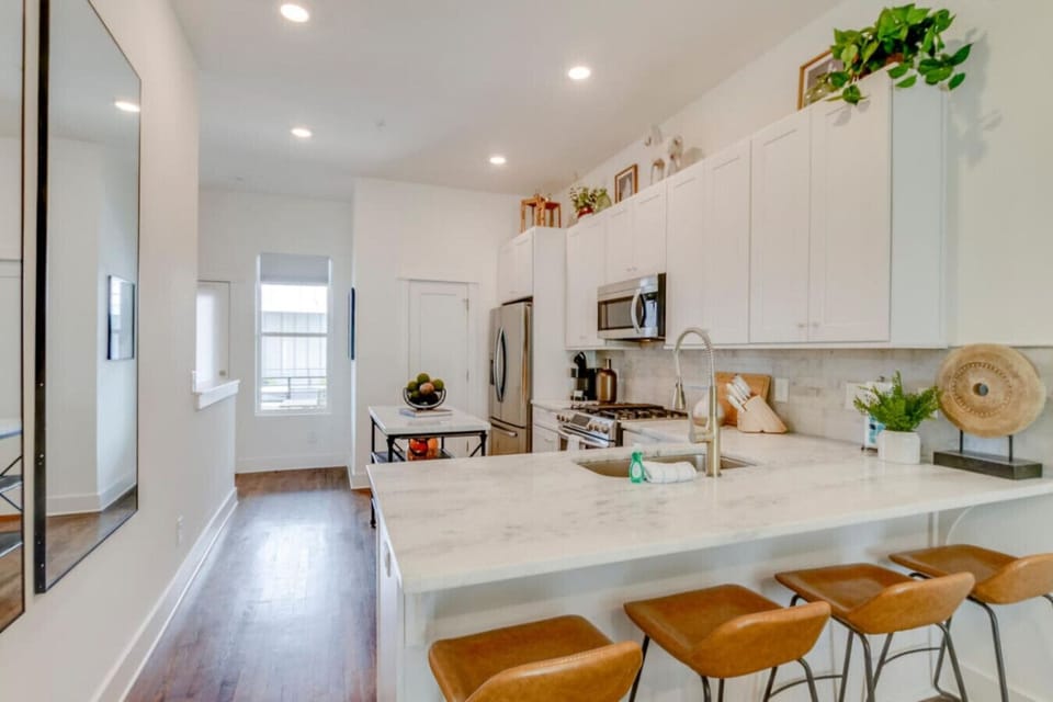 Kitchen island close-up with marble countertop, bar stools, and stainless appliances