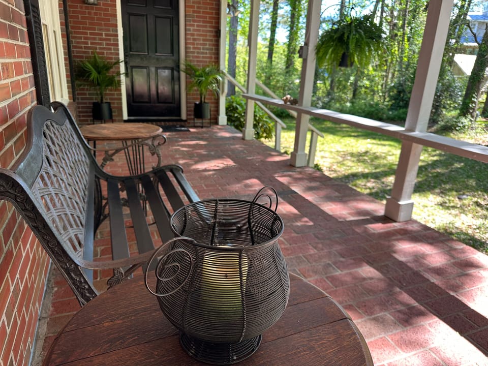 Front porch view of bench and side tabels