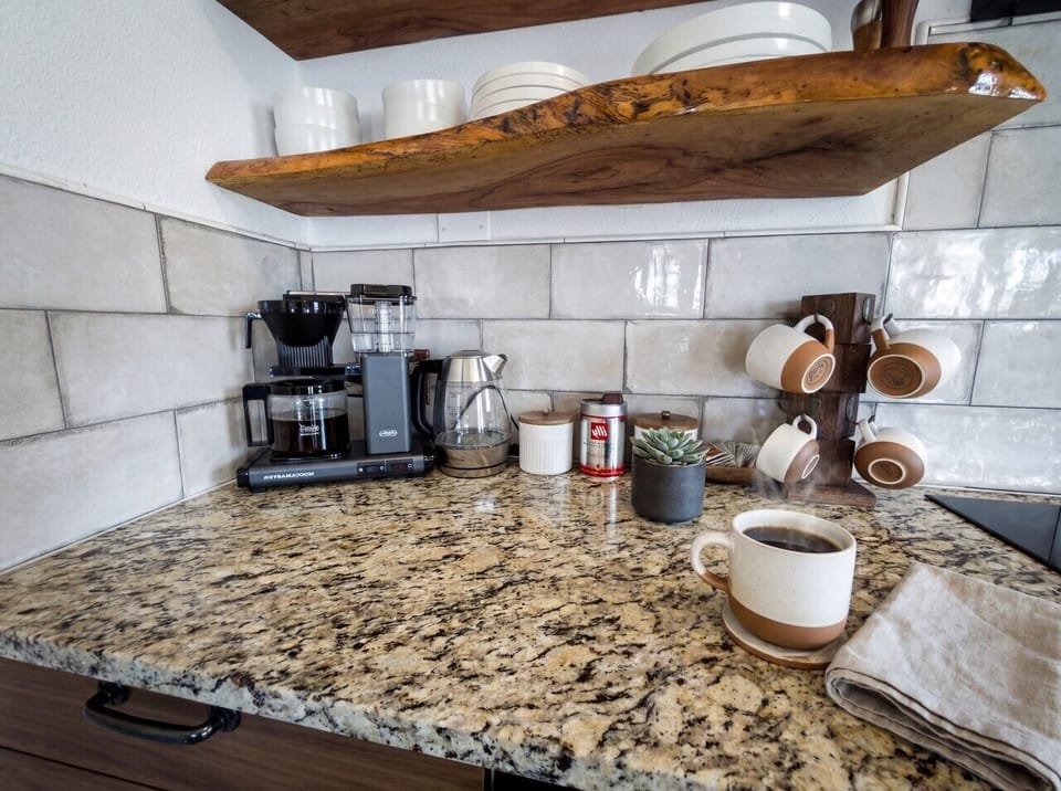 Moccamaster brewer with premium Lavazza coffee and ceramic mugs. Coffee, tea and creamer stocked for your stay.