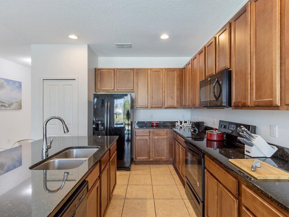 Modern kitchen w/ stainless appliances, granite counters, & warm wood cabinets.