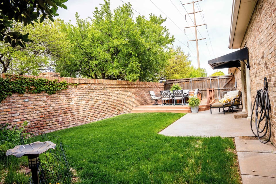 The walled backyard: real grass, patio dining under the awning, and room for the dog to patrol.